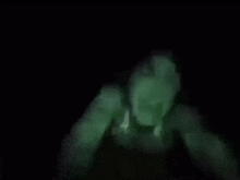 a blurry picture of a person in the dark with a green light coming out of their mouth .