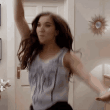 a woman in a tank top is dancing in a living room .