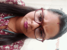 a close up of a woman wearing glasses and a maroon shirt