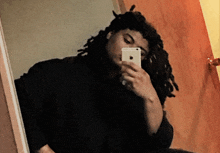 a man with dreadlocks is taking a picture of himself in a mirror