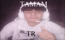 a man wearing headphones giving a thumbs up with the words tamam tr on the bottom right