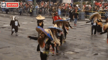 a group of people wearing sombrero hats are walking down a street in front of a crowd with a sign that says en vivo