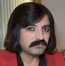 a man with long hair and a mustache is wearing a red jacket and black shirt