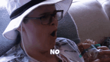 a woman wearing glasses and a hat is saying no