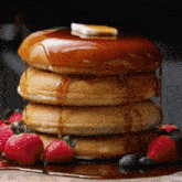 a stack of pancakes with syrup and berries on top