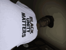 a man wearing a white t-shirt that says black unity matters