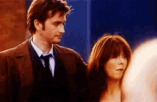 a man and a woman are standing next to each other . the man is wearing a suit and tie .