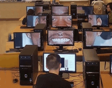 a man sits at a desk in front of a computer monitor with a picture of a smiling face on it