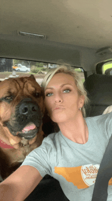 a woman in a grey t-shirt with the state of tennessee on it is sitting in a car with a dog