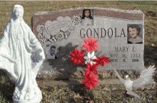 a statue sits next to a gravestone for condola mary e.