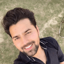 a man with a beard and a black shirt smiles for the camera