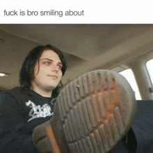 a man in a black shirt is smiling while holding a shoe in his hand