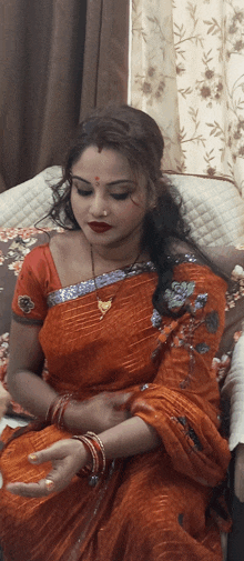 a woman in a red saree sits in a chair