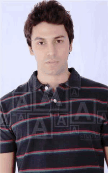 a man wearing a striped polo shirt is standing in front of a studio logo