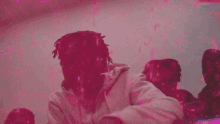 a man with dreadlocks is sitting in front of a crowd of people in a pink room .