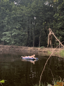 a person floating on a raft in a lake with trees in the background