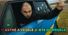 a man sitting in a car with the words stastne a vesele jdete do prdele written below him