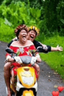 two women are riding a yellow scooter down a road .