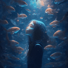 a girl is looking up at a flock of fish in the ocean .