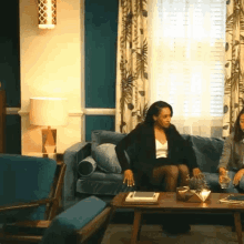 two women are sitting on a couch in a living room talking