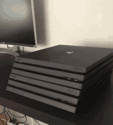 a stack of sony ps4s sits on a desk