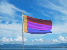 a rainbow flag is flying in front of a blue sky