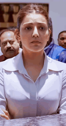 a woman in a white shirt stands in front of a crowd of people