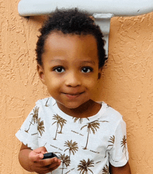 a young boy wearing a shirt with palm trees on it is smiling