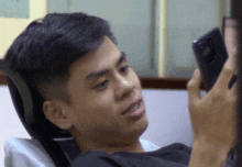 a young man is looking at his phone and making a face