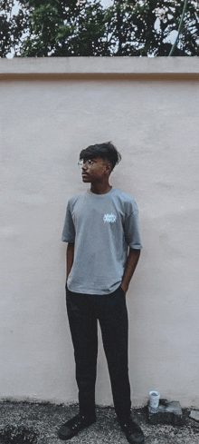 a young man wearing a gray shirt with the word swag on it stands in front of a wall