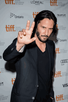 a man giving a peace sign in front of a sign that says tiff on it