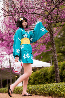 a girl in a blue kimono holding a mask