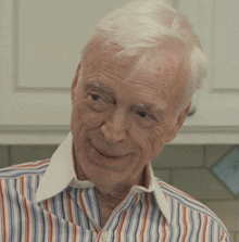 an older man wearing a striped shirt is smiling for the camera