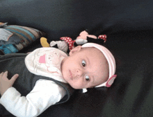 a baby wearing a bib with pigs on it is laying on a black couch