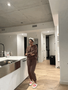 a woman wearing a headband stands in a kitchen