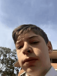 a young boy is taking a selfie in front of a building and trees .