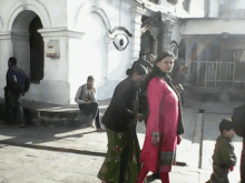 a group of people are walking down a street in front of a building with a large eye painted on it .