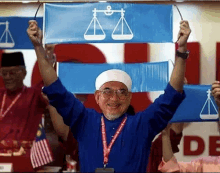 a man in a blue shirt is holding up a sign with a scale of justice on it