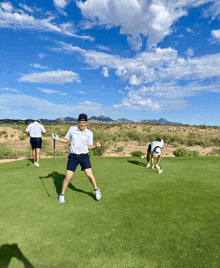 a man is standing on a golf course with his arms outstretched