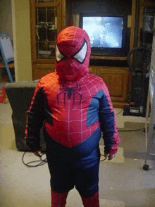 a child in a spider man costume is standing in front of a television .