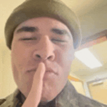 a man wearing a hat is holding his finger to his mouth .