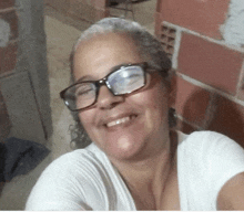 a smiling woman wearing glasses and a white shirt