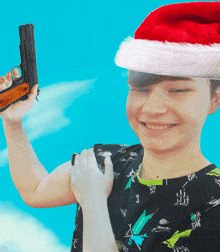 a young boy wearing a santa hat holds a gun