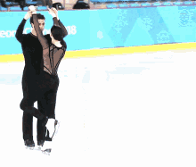 a man and a woman are dancing on a ice rink with a sign behind them that says ' ice ' on it