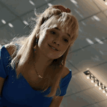 a woman wearing a blue shirt and earrings smiles