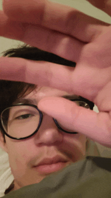 a man wearing glasses is covering his face with his fingers