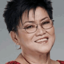 a close up of a woman wearing glasses and a red shirt smiling .