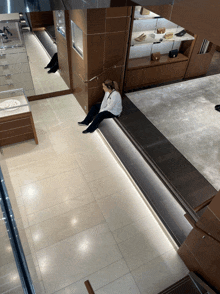 a woman sits on a ledge in a store