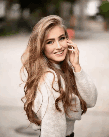 a woman with long hair is smiling while talking on a phone