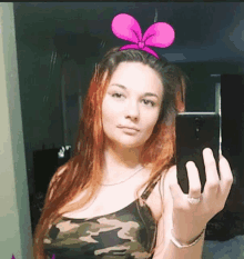 a woman takes a selfie with a pink bow in her hair